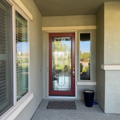 Front entrance of a house with a red door, welcome mat, and beige walls.