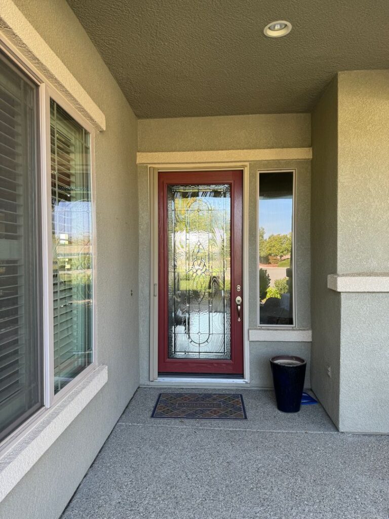 Front entrance of a house with a red door, welcome mat, and beige walls.