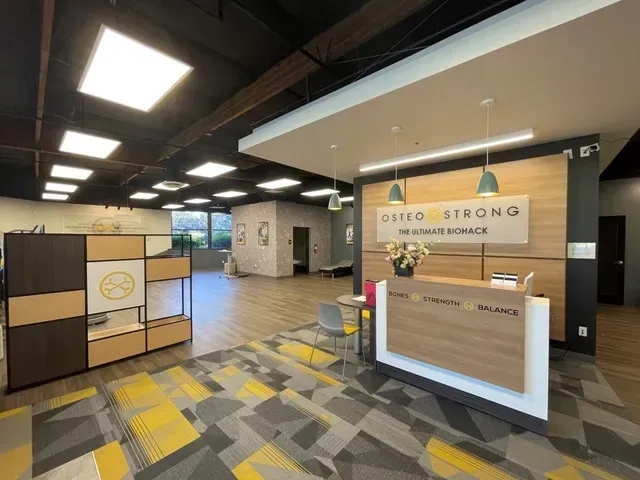 Interior view of OsteoStrong business with reception desk and modern decor.